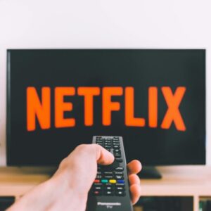 A hand holding a TV remote in front of a screen with Netflix, perfect for streaming and movie night themes.